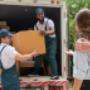 two-men-movers-in-blue-uniform-lift-cardboard-box